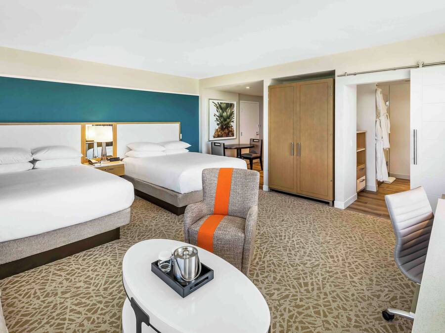 Een hotelkamer met twee bedden, een eettafel, een stoel, een salontafel en een kledingkast.