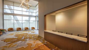 Un espace d’accueil moderne doté d’une grande fenêtre, d’un tapis à motifs et d’un comptoir de réception.