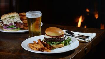 Un repas composé d’un hamburger, de frites et d’une bière, servis sur une table en bois.