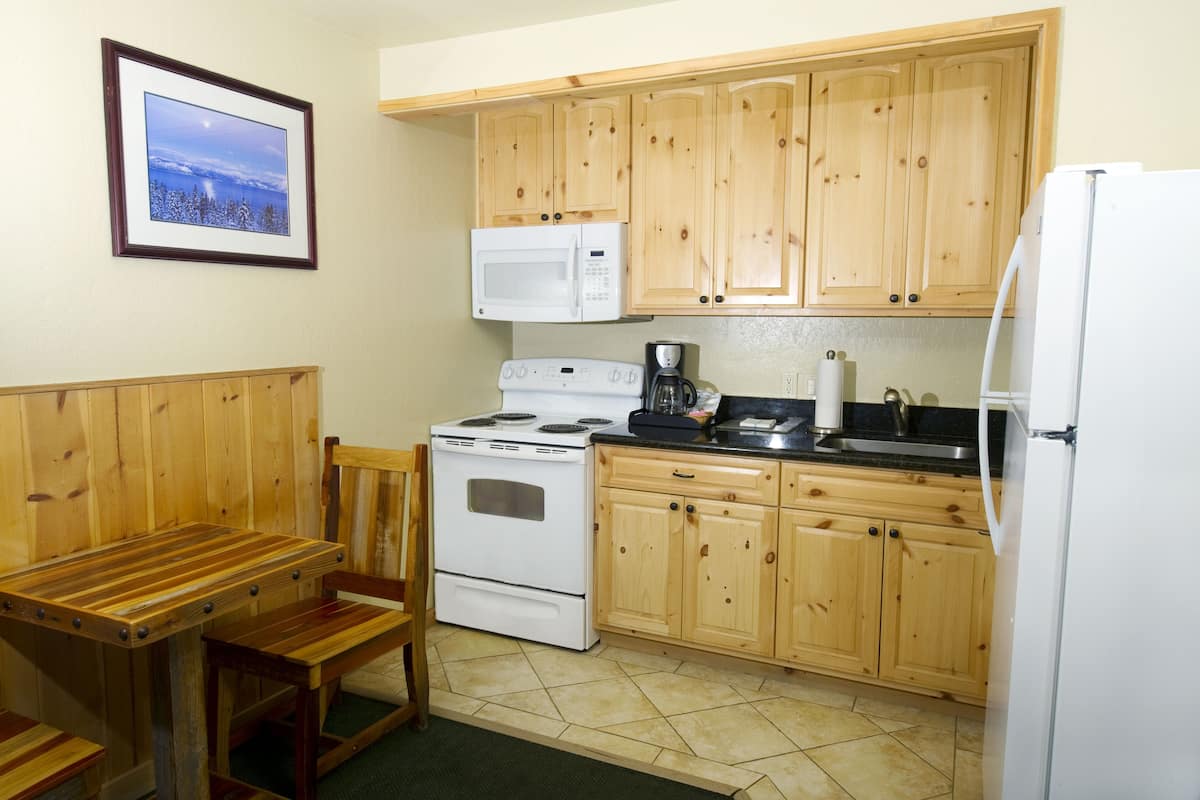 A compact kitchen with wooden cabinets, a white stove, a microwave, and a refrigerator.