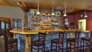 A bar area with a stone counter, wooden chairs, and hanging lights.