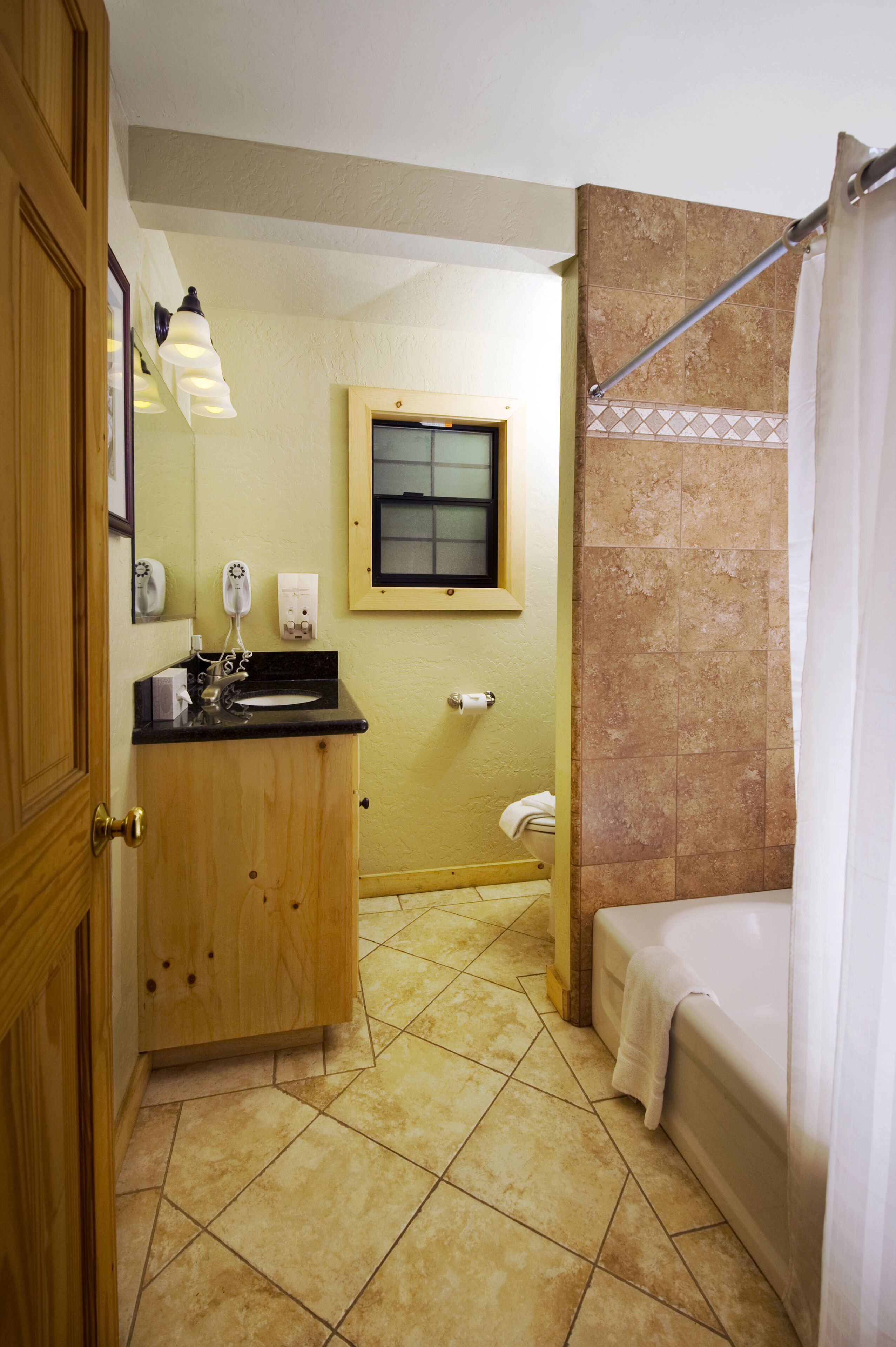 A bathroom with a wooden vanity, a sink, a window, and a bathtub.
