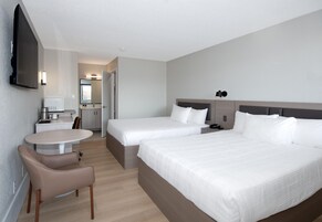 Habitación de hotel con dos camas, un escritorio, una silla, un televisor y un baño.