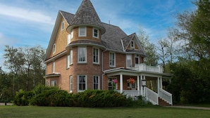 A large, two-story house with a distinctive tower and a wrap-around porch.