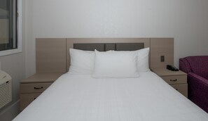 A hotel room with a bed, a bedside table, a nightstand, a telephone, and a window. - Coast Red Deer Hotel (Red Deer)