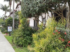 A lush garden with various plants and a sign for Villa Rosa A Fine Inn. - Villa Rosa Inn (Santa Barbara)