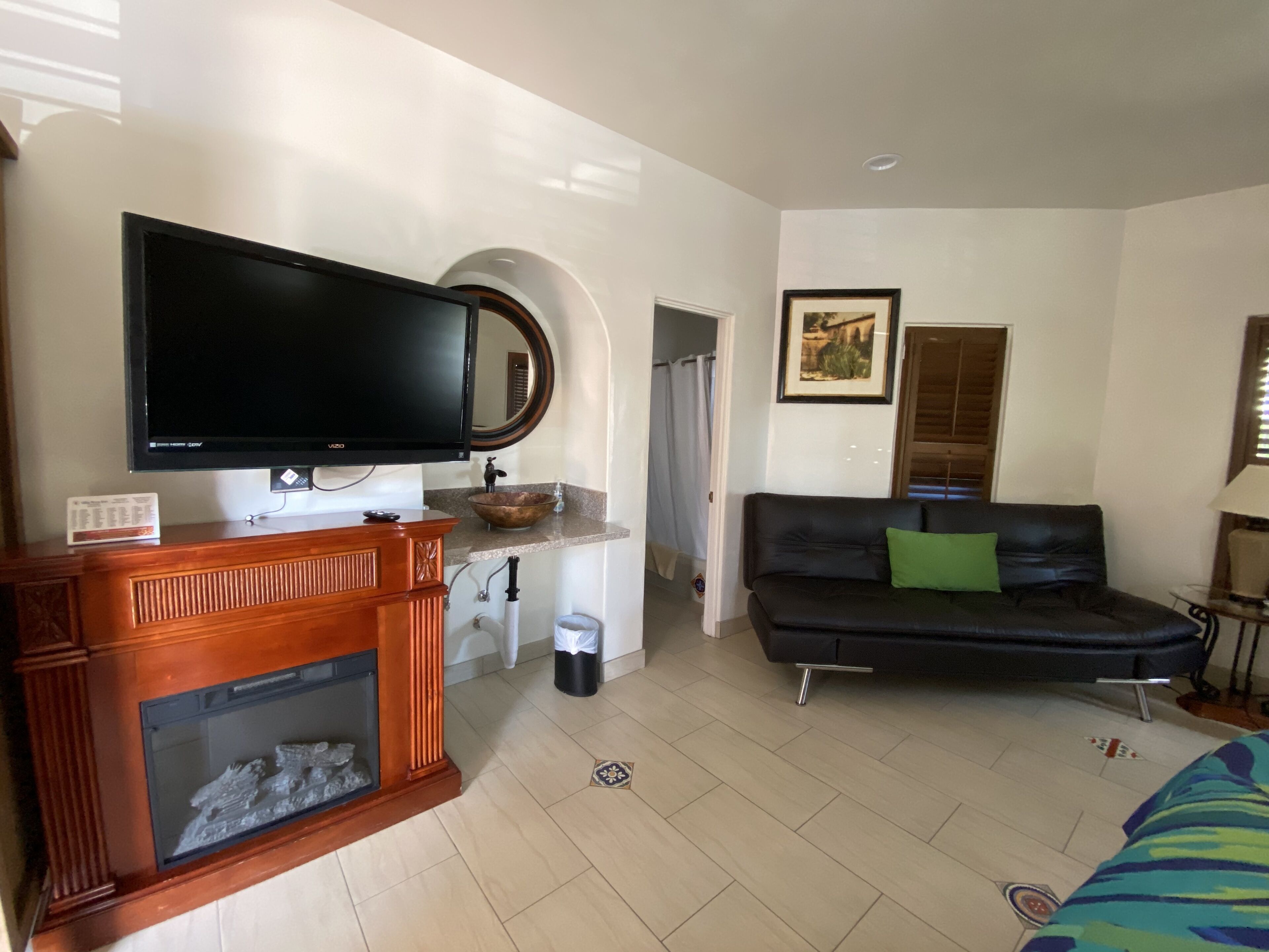 A living room with a television, fireplace, sofa, and a framed picture on the wall.