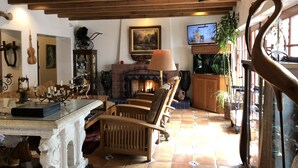 Ein gemütliches Wohnzimmer mit Kamin, Holzmöbeln, einem Fernseher und einer Treppe.