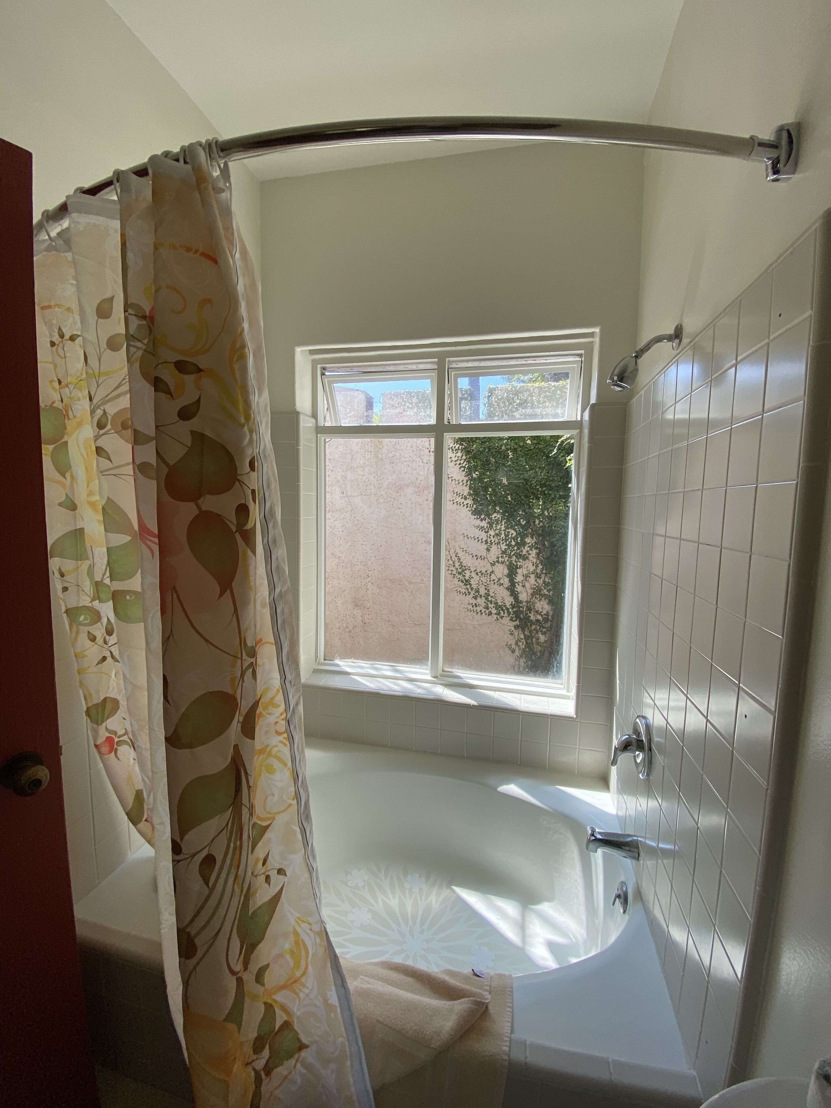 A bathroom with a bathtub, a window, and a shower curtain.