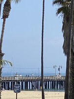A pier with a sign indicating directions to parking and a beach area.