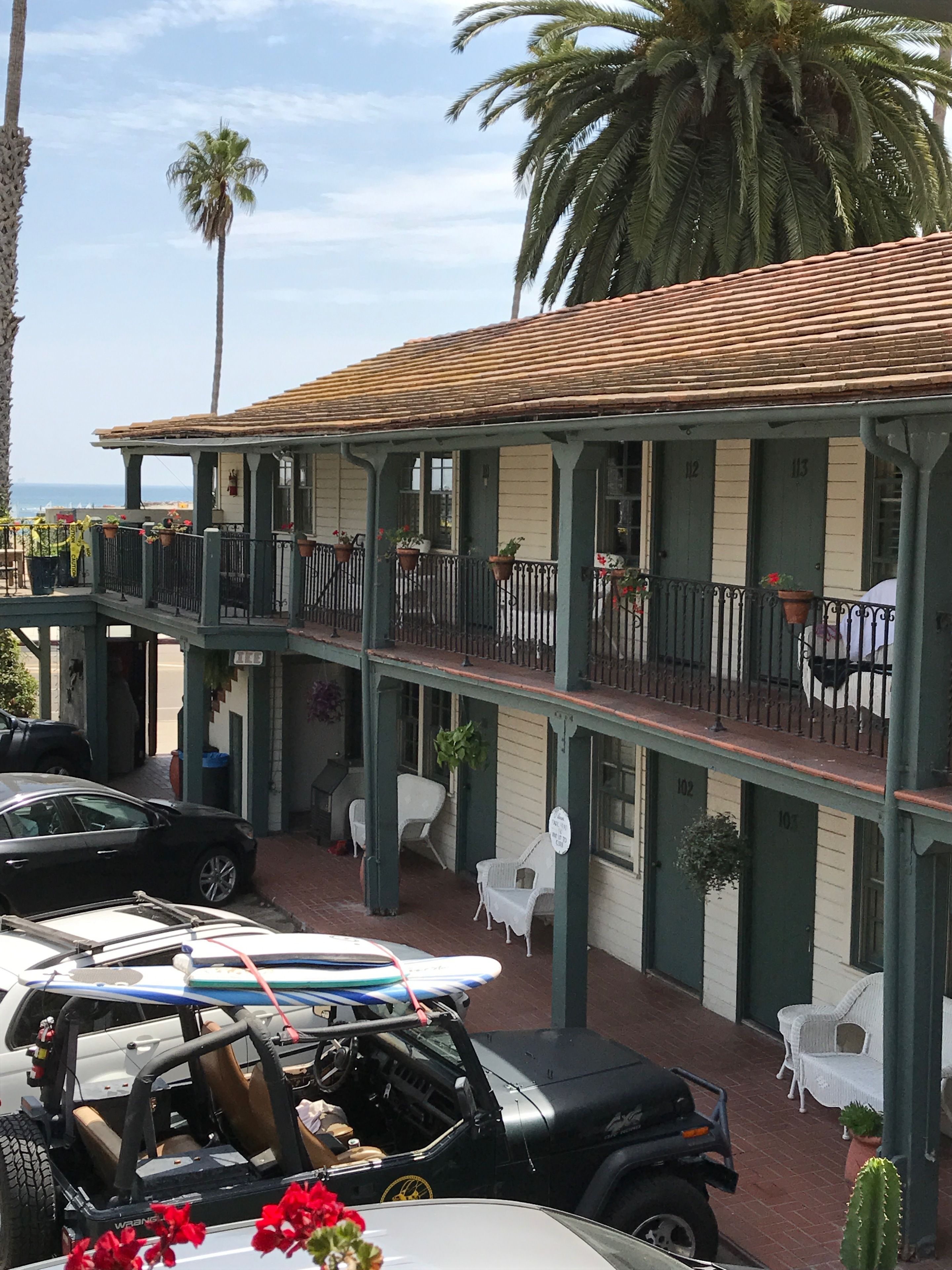 Un edificio con un balcone, piante in vaso e una tavola da surf.