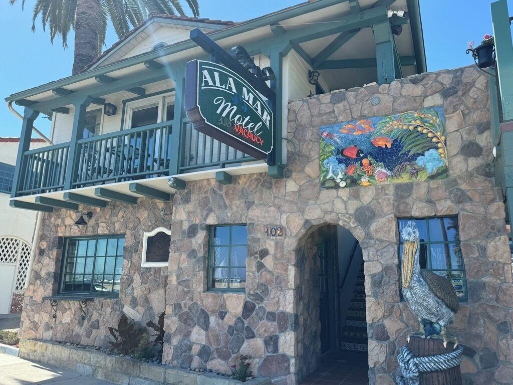 A motel with a stone facade, a balcony, and a mural of tropical fish.