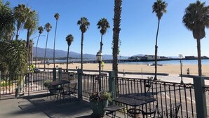 A seaside patio with tables and chairs, palm trees, and a view of the beach and ocean. - Ala Mar by the Sea (Santa Barbara)