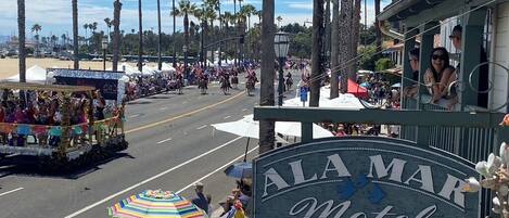 A street view with a motel sign, palm trees, and a parade.