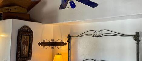 A bedroom with a bed, a ceiling fan, a bedside lamp, and a framed picture on the wall.