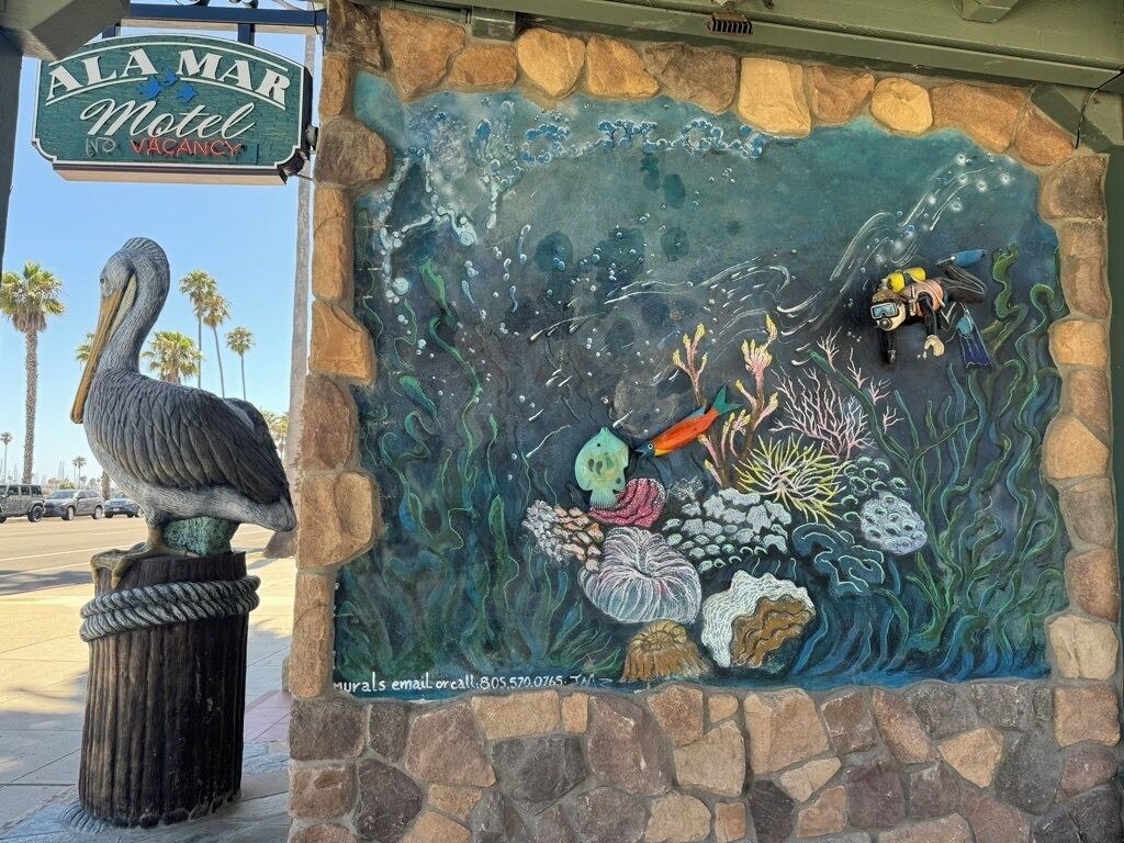 A mural of an underwater scene with a pelican and scuba divers, and a sign for the Ala Mar Motel.