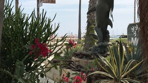 A dolphin statue in a garden with cacti and red flowers. - Ala Mar by the Sea (Santa Barbara)