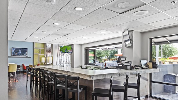 A modern bar area with a long counter, multiple bar stools, and a television screen.