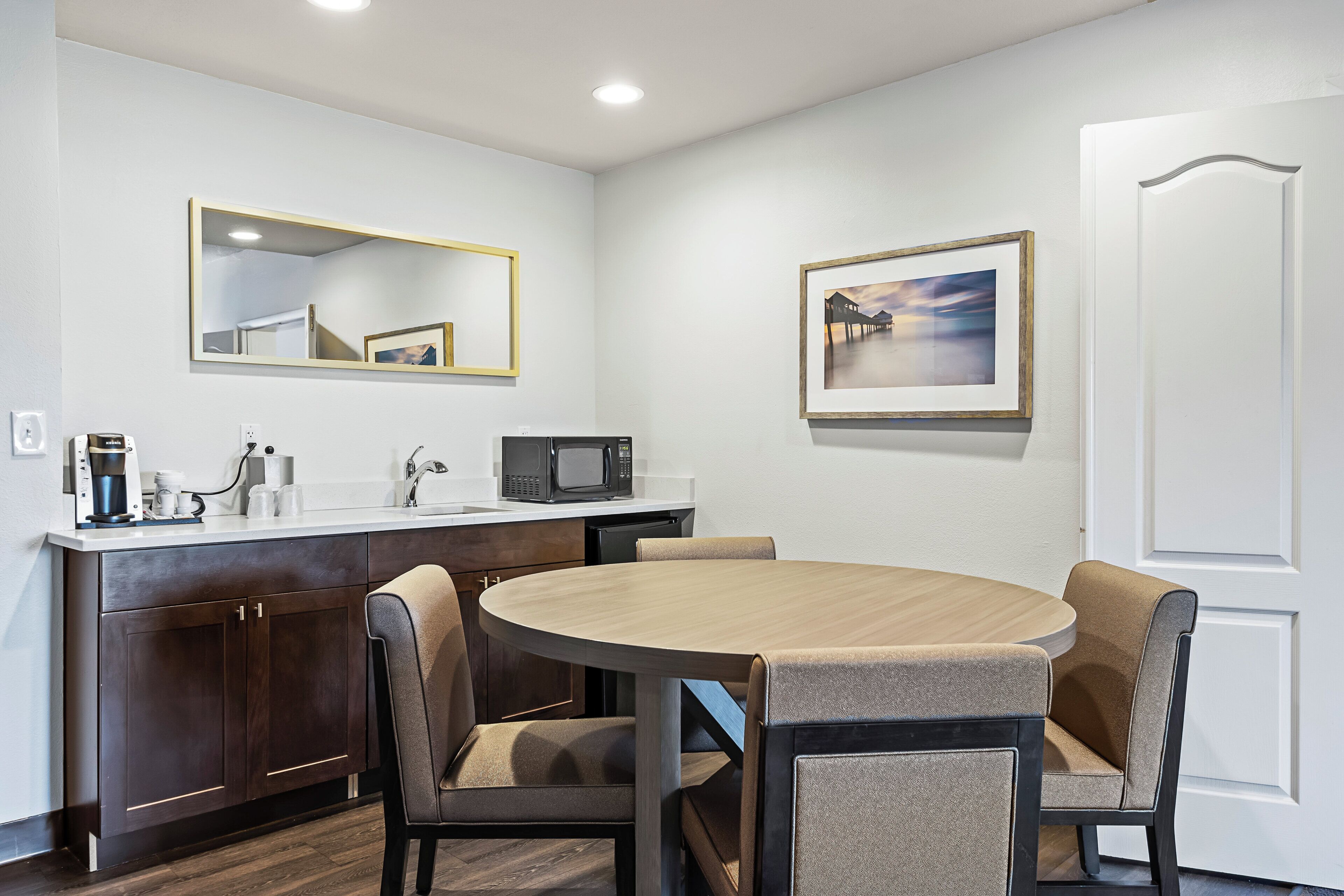 Una cocina compacta con una mesa redonda de comedor, dos sillas, un microondas y una cafetera.