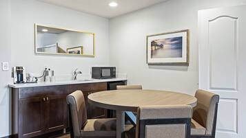 Una cocina compacta con una mesa redonda de comedor, dos sillas, un microondas y una cafetera.