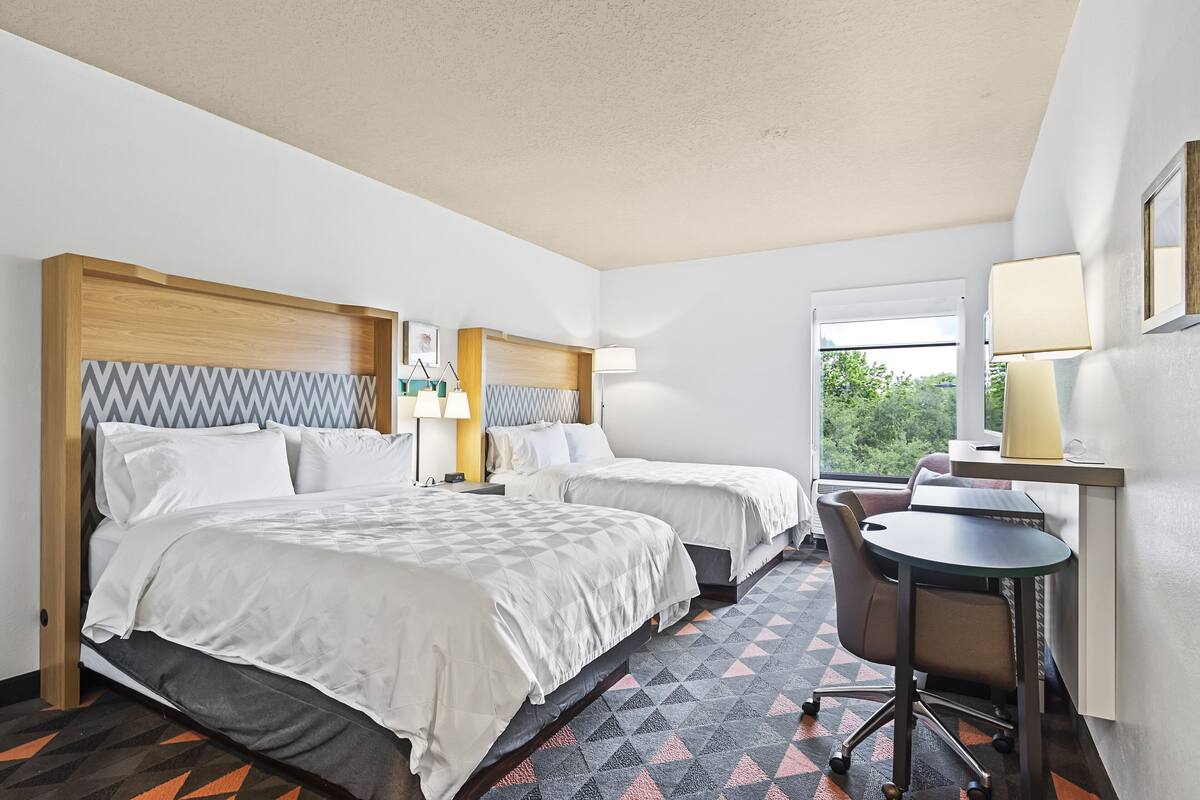 Une chambre d’hôtel avec deux lits, un bureau et une chaise.