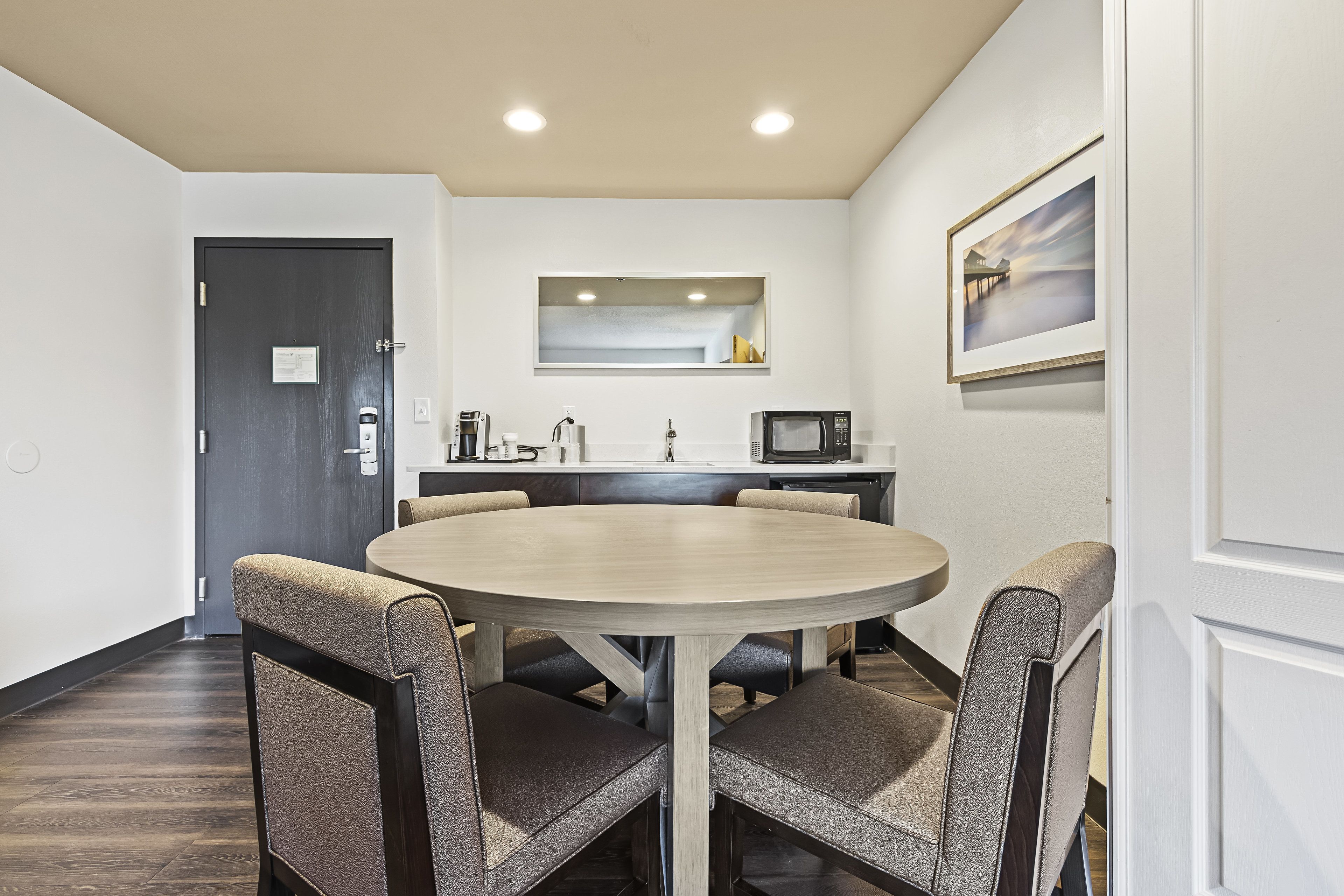 A modern kitchen with a round dining table and four upholstered chairs.