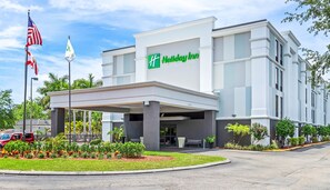 Un hôtel Holiday Inn doté d’une entrée couverte, d’un mât pour drapeau et d’un jardin aménagé.