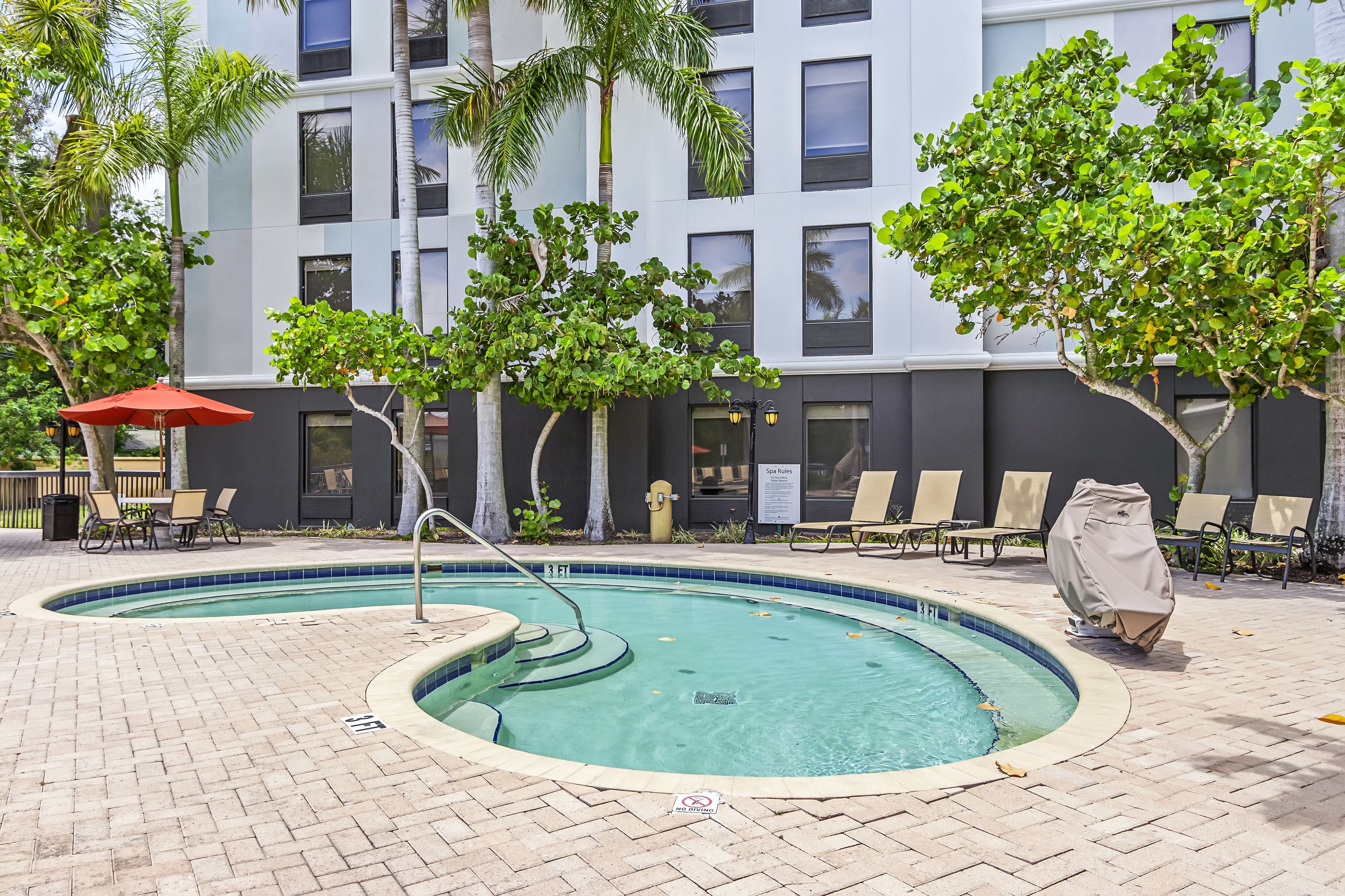 A pool area with a circular pool, lounge chairs, and a covered seating area.