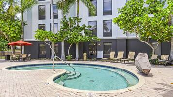 A pool area with a circular pool, lounge chairs, and a covered seating area.