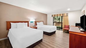 A hotel room with two beds, a desk, a chair, a TV, and a window with curtains.