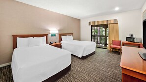 A hotel room with two beds, a desk, a chair, a TV, and a window with curtains.