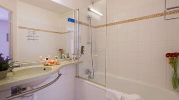 A bathroom with a sink, mirror, shower, and bathtub.