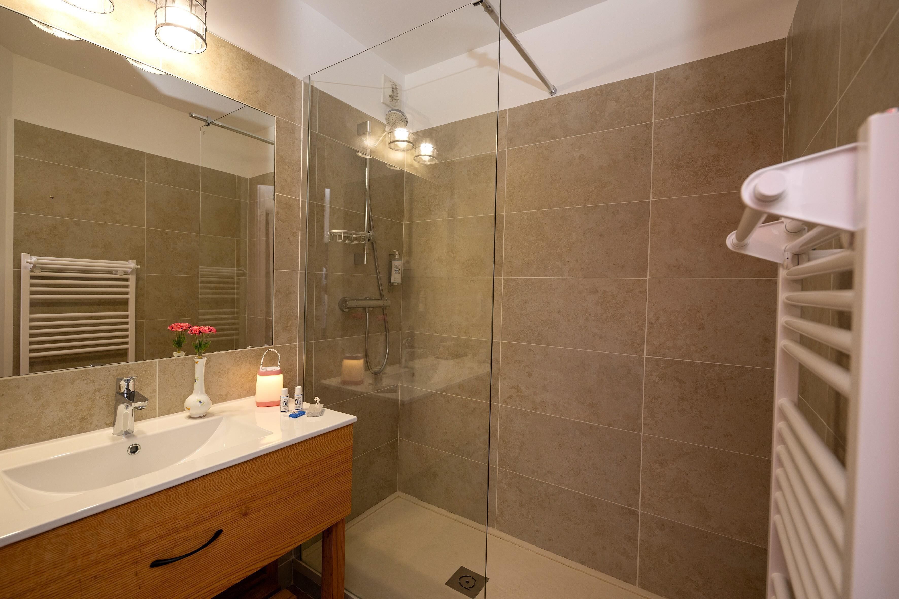 Une salle de bain moderne avec une douche à parois de verre, un lavabo blanc et un miroir au-dessus.