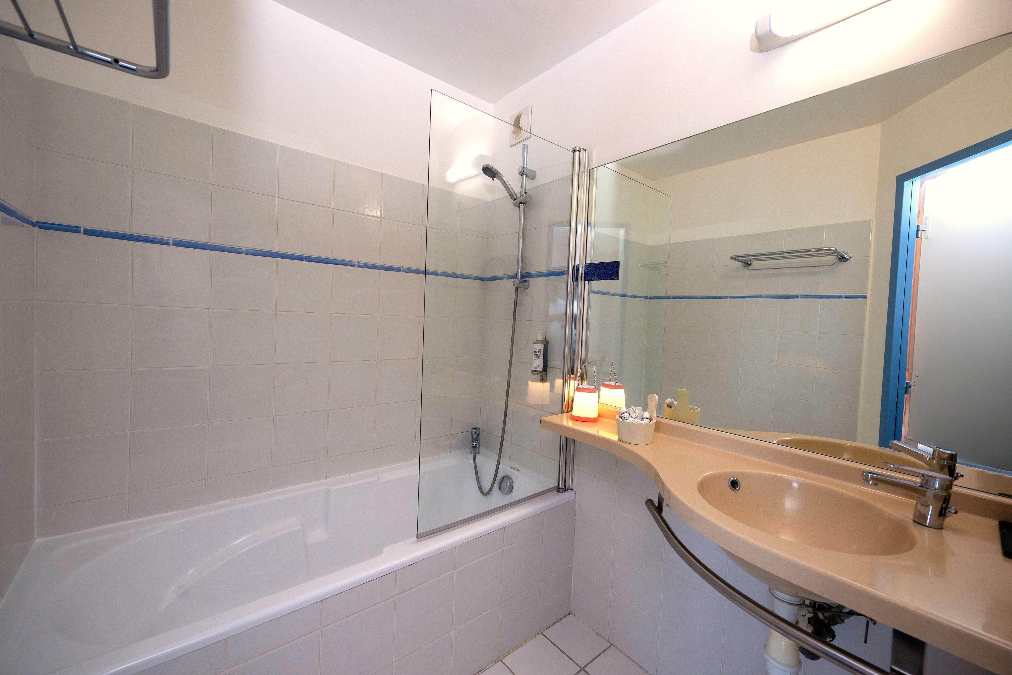 A bathroom with a bathtub, a shower, a sink, and a mirror.