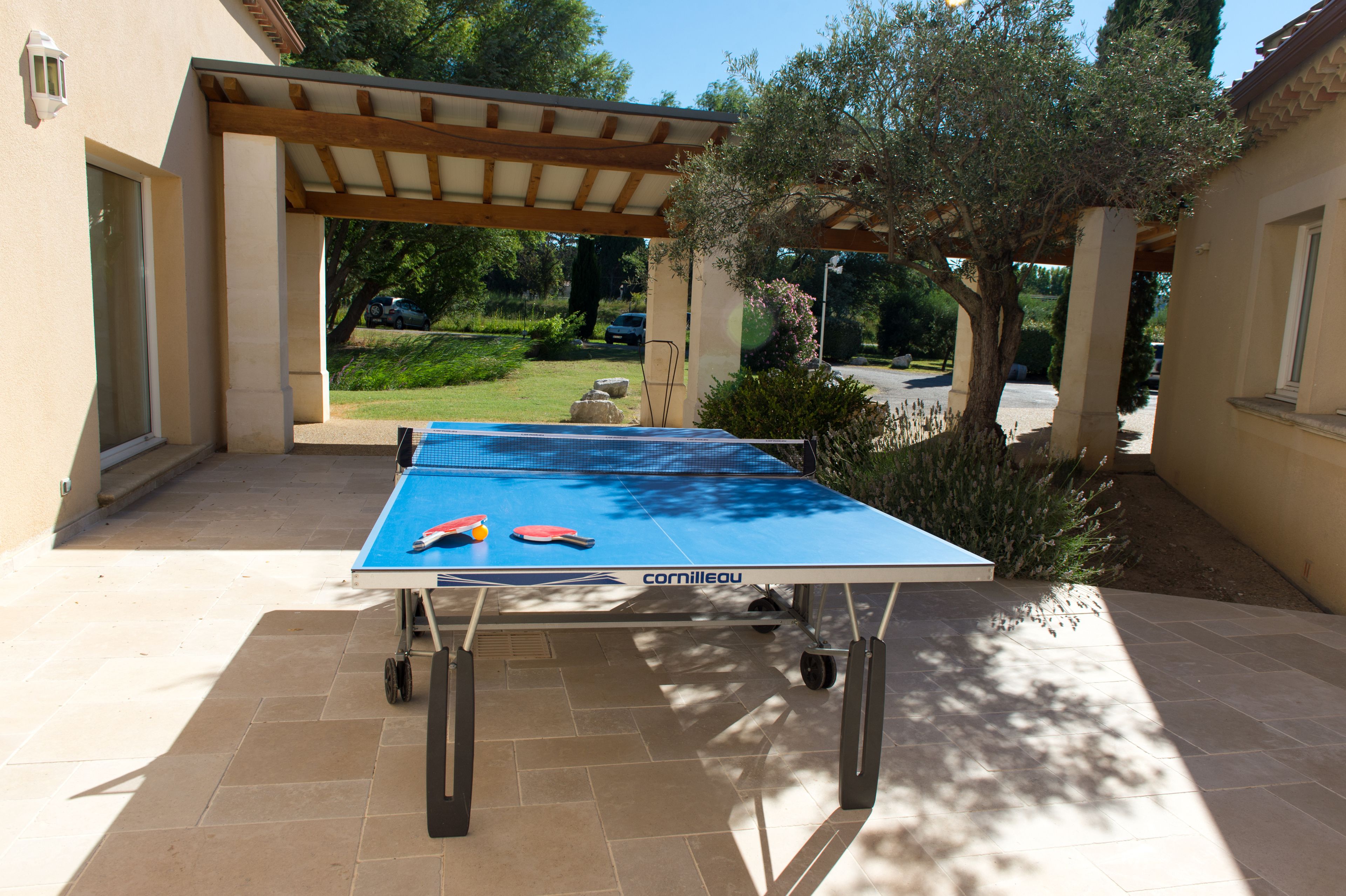 A ping pong table in an outdoor patio area with a pergola overhead.