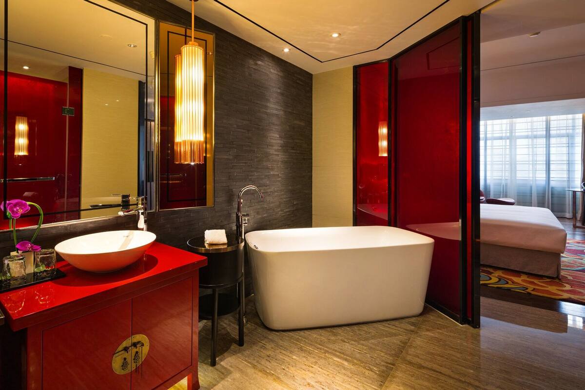 Une salle de bain moderne avec un grand lavabo ovale, une baignoire sur pieds et un miroir agrémenté d’un luminaire suspendu.