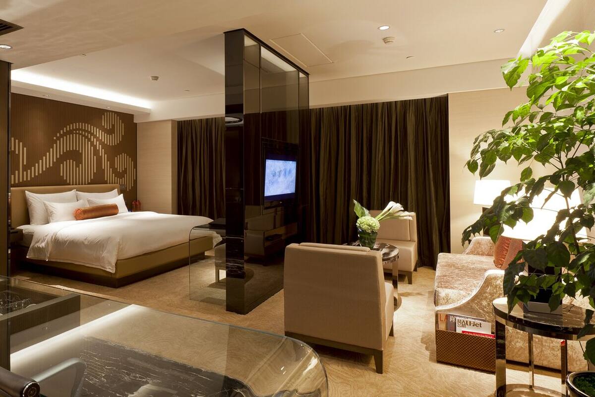 Une chambre d’hôtel moderne équipée d’un lit, d’une télévision, d’un coin salon et d’une table basse en verre.