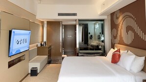 Habitación de hotel moderna con una cama grande, televisión de pantalla plana, escritorio y baño con un espejo amplio.