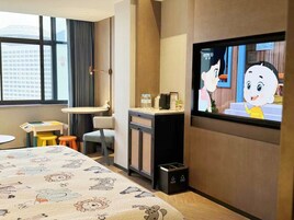 Una camera d'albergo con un letto, una televisione, una scrivania e una finestra vista edifici.