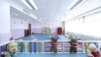 A children's playroom with a blue floor, white walls, and a white ceiling. There are toys and a teddy bear on the floor.