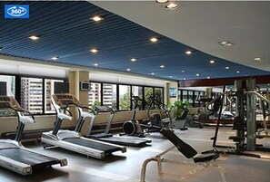 Un gimnasio con cintas de correr, bicicletas estáticas y máquinas de pesas.