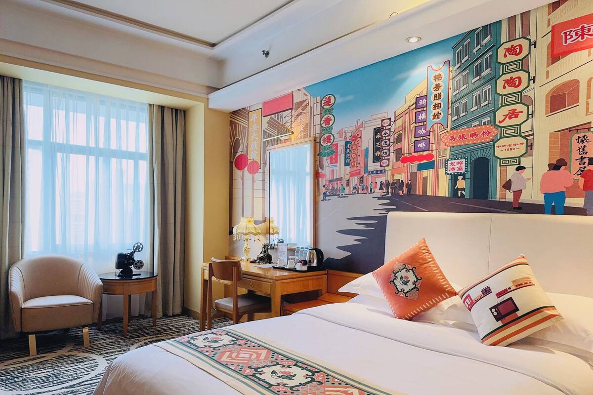 Une chambre d’hôtel avec un grand lit, un bureau, une chaise et une fenêtre avec des rideaux.