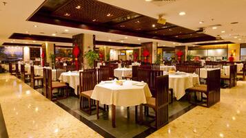 Un restaurante espacioso con varias mesas y sillas, piso pulido y un diseño de techo moderno.