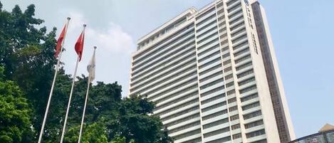 A tall, modern building with horizontal windows and a flagpole with flags in front.