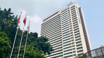 Un edificio alto y moderno con ventanas horizontales y una asta con banderas al frente.