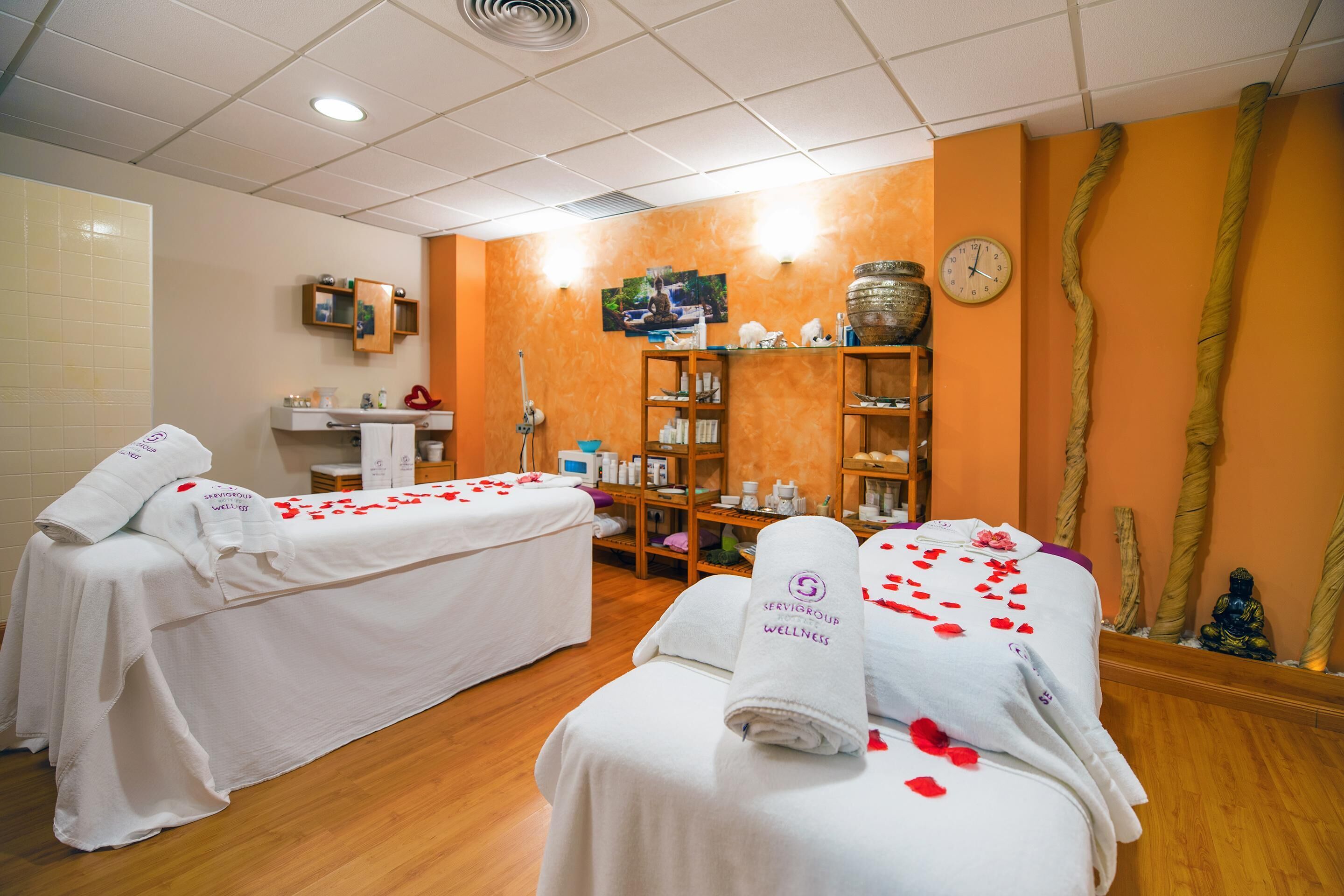 A wellness center with two massage tables, a reception area, and a shelf with wellness products.
