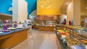 Zona de bufé con un cartel de 'Show Cooking', diferentes estaciones de comida y un diseño de interiores moderno.