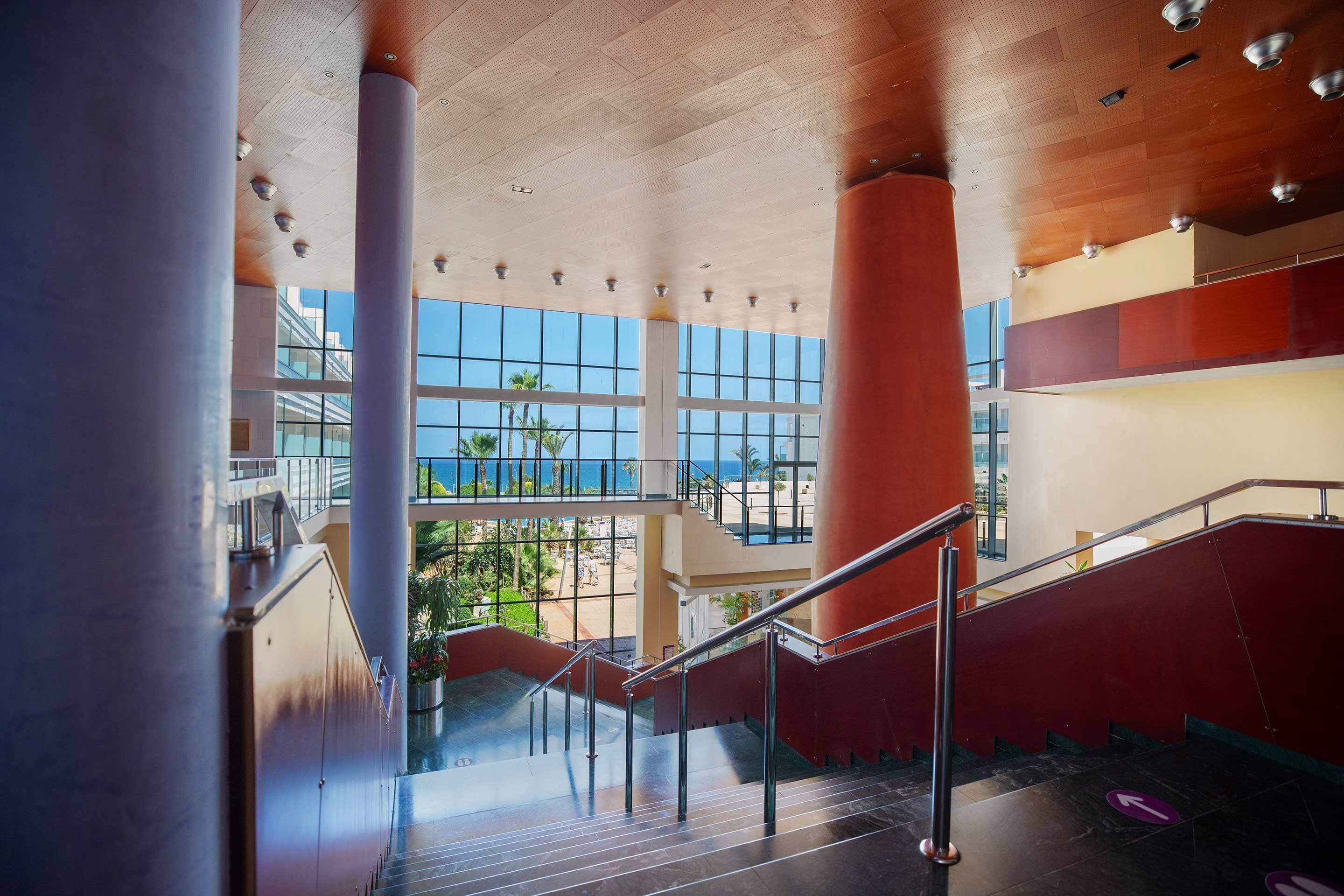 Um interior moderno com escada, janelas amplas e vista para a praia.