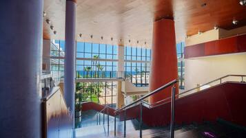 Un interior moderno con una escalera, ventanas amplias y vistas a la playa.