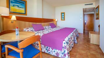 Une chambre d’hôtel avec un lit, une table, des chaises et un petit bureau.